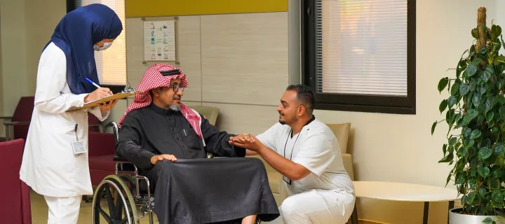 رجل على كرسي متحرك يتحدث مع طبيب وممرضة